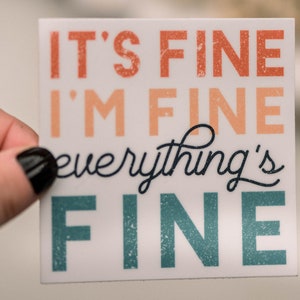 Peut inclure: Autocollant blanc avec le texte "It's fine I'm fine everything's fine" en lettres orange, p&ecirc;che et turquoise.