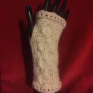 May include: White knitted fingerless gloves with a cable knit pattern and a decorative edge.