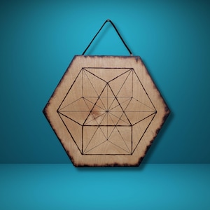 May include: Hexagonal wooden wall art with a geometric design burned into the wood. The artwork features a central star pattern within a larger geometric shape. A black cord is attached for hanging.