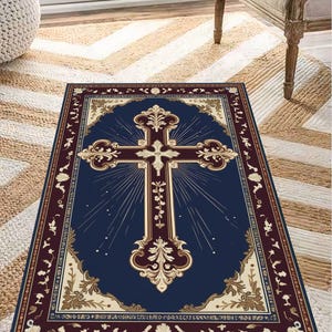 May include: A navy blue rug with a gold and white cross design. The cross is surrounded by a decorative border of gold and white floral patterns. The rug has a burgundy border.