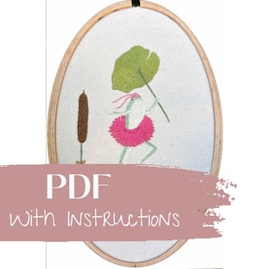 May include: An oval embroidery hoop with a whimsical frog design. The frog is wearing a pink tutu and holding a green leaf. A brown cattail is on the left. The text "PDF with Instructions" is across the bottom.