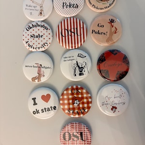 May include: A collection of thirteen circular pin-back buttons featuring various Oklahoma State University designs, including text like Go Pokes, OSU, and Boone Pickens Stadium, with illustrations of mascots, cheerleaders, and football-themed graphics.