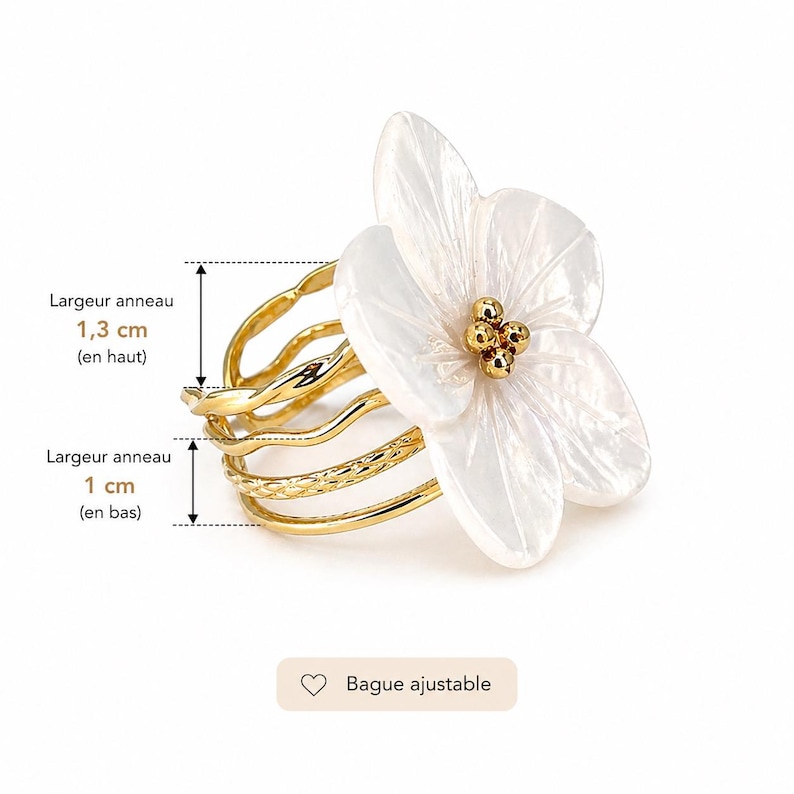 May include: A gold-toned ring with a white flower design. The ring features a multi-band design with a textured band and a flower with gold accents. The ring's width is 1.3 cm at the top and 1 cm at the bottom. The text "Adjustable ring" is also present.