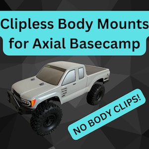 Puede incluir: Un camión RC Axial Basecamp blanco con una carrocería negra y gris, ruedas negras y un interior negro y gris. El camión está sobre un fondo gris con el texto "Clipless Body Mounts for Axial Basecamp" y "NO BODY CLIPS!" en azul.