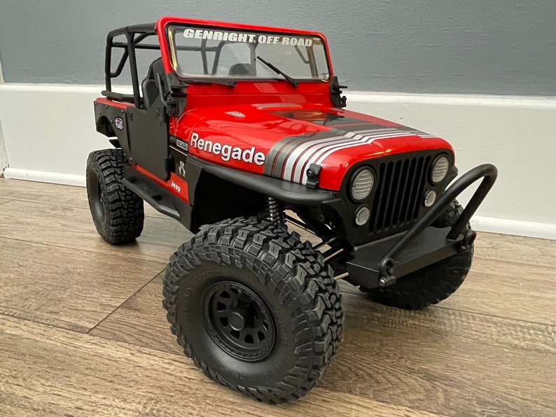 May include: Red Jeep Renegade toy car with black wheels, a black roll cage, and a black front bumper with a black bull bar. The car has a white and silver stripe on the hood and the words "Genright Off Road" on the windshield.