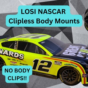 Può includere: Un'auto da corsa NASCAR gialla e nera con il numero 12 e le parole "Menards" e "Great Stuff" sul lato. L'auto è un Losi Clipless Body Mount. Il testo "No Body Clips!!" è in primo piano.