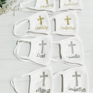 Op de afbeelding: Set witte gezichtsmaskers met een gouden kruis en een andere naam op elk masker. De namen zijn Mommy, Godmother, Daddy, Godfather, Dad, Auntie, Mama en Godfather.