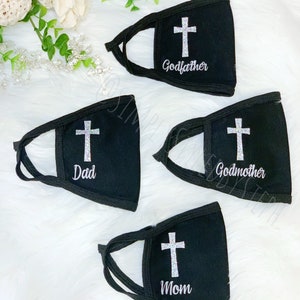 Op de afbeelding: Vier zwarte gezichtsmaskers met een wit kruis en tekst. De maskers hebben de tekst "Peter", "Peetmoeder", "Vader" en "Moeder".