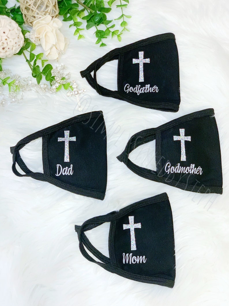 Op de afbeelding: Vier zwarte gezichtsmaskers met een wit kruis en tekst. De maskers hebben de tekst "Peter", "Peetmoeder", "Vader" en "Moeder".