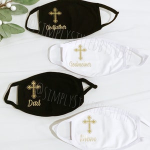 Op de afbeelding: Vier gezichtsmaskers met een gouden kruisontwerp en verschillende tekst. De maskers zijn wit en zwart. De tekst op de maskers luidt "Peter", "Peetmoeder", "Papa" en "Mama".