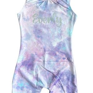 May include: A purple, blue, and white tie-dye leotard with the name "Evelyn" written in silver glitter.