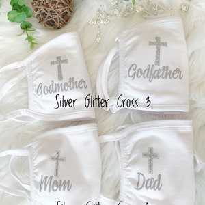 Op de afbeelding: Vier witte gezichtsmaskers met zilveren glitterkruisen en de woorden "Peter", "Meter", "Moeder" en "Vader" erop gedrukt.  Silver Glitter Cross 3 en Silver Glitter Cross 2 zijn onder de maskers gedrukt.