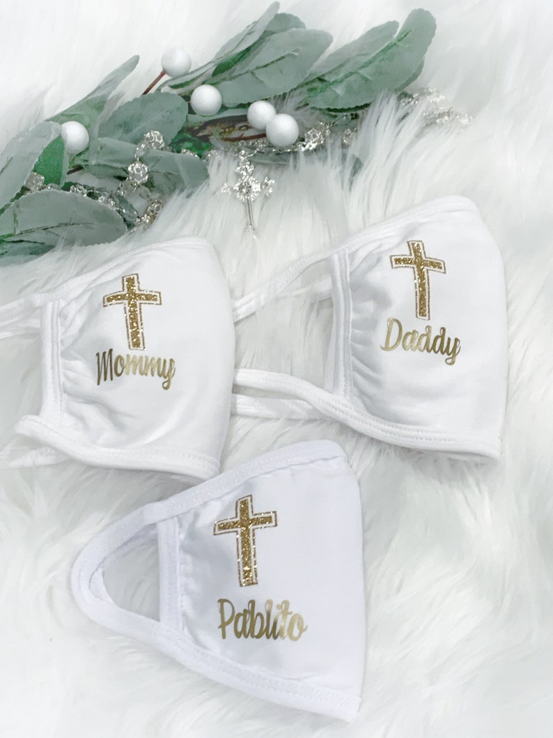 Op de afbeelding: Drie witte gezichtsmaskers met gouden glitterkruisen en gepersonaliseerde tekst. De maskers hebben de tekst "Mommy", "Daddy" en "Pablito".