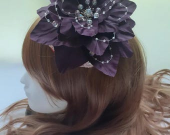 Un gran tocado floral morado decorado con cuentas para fiestas de té y carreras de caballos.