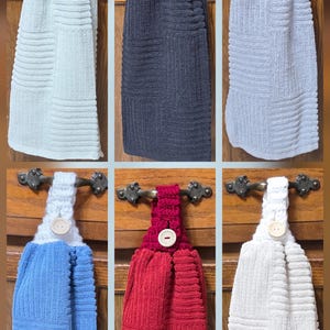 May include: Six hanging kitchen towels featuring a textured, ribbed fabric design. Each towel includes a crocheted top loop secured with a single wooden button, available in light blue, black, grey, blue, red, and white color variations.