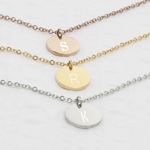 May include: Three gold necklaces with initial pendants. The top necklace has a rose gold pendant with the letter "S", the middle necklace has a gold pendant with the letter "R", and the bottom necklace has a silver pendant with the letter "K".