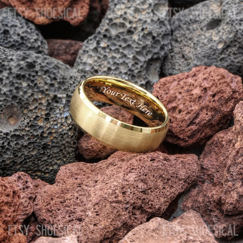 May include: A gold-toned ring with a brushed matte exterior finish and a polished interior band. The inner surface of the ring features the engraved text "Your Text Here" in a clear, sans-serif font, visible from the side angle.