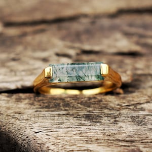 May include: A gold ring with a rectangular green moss agate stone.
