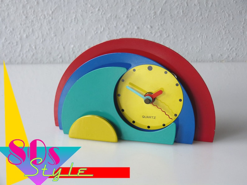 May include: A colorful, abstract clock with a yellow face, red and blue hands, and a red, blue, green, and yellow base. The clock says "QUARTZ" on the face.