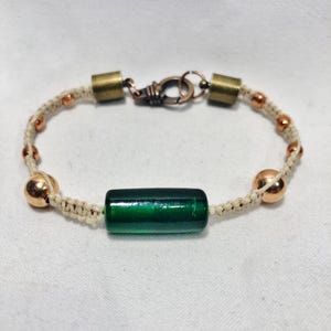 May include: A green glass bead bracelet with copper accents and a white cord.