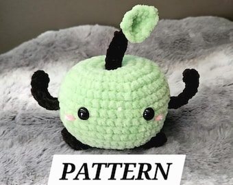 May include: A crocheted apple-shaped plush toy in light green with black arms, stem, and base. The apple has black eyes and pink cheeks. The word "PATTERN" is printed on a white rectangle below the toy.