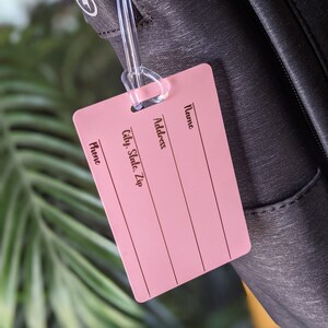 May include: Pink luggage tag with the words "Name", "Address", "City, State, Zip", and "Phone" printed on it.