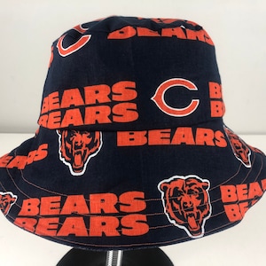May include: A blue bucket hat with a repeating pattern of orange "Bears" text and a bear logo. The hat also features a large orange "C" in the center.