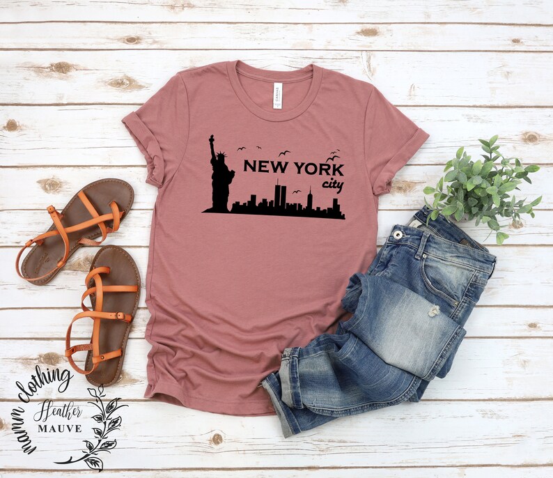 May include: A heather mauve t-shirt with a black graphic of the Statue of Liberty and the New York City skyline. The text "NEW YORK city" is printed on the shirt.