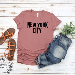May include: A heather mauve t-shirt with the text "NEW YORK CITY" printed in black.