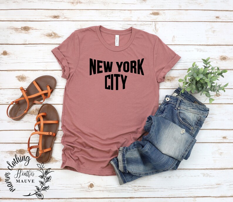 May include: A heather mauve t-shirt with the text "NEW YORK CITY" printed in black.