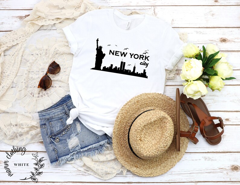 May include: White t-shirt with a black graphic of the Statue of Liberty and the New York City skyline. The text "NEW YORK city" is printed below the graphic.