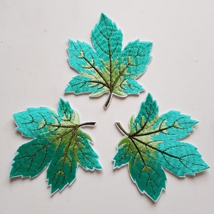 May include: Three embroidered green and turquoise maple leaf patches.