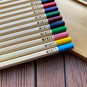 May include: A set of 10 wooden pencils with the name "WYATT" engraved on each pencil. The pencils are painted in different colors, including red, maroon, navy blue, green, burgundy, dark blue, pink, yellow, and blue.