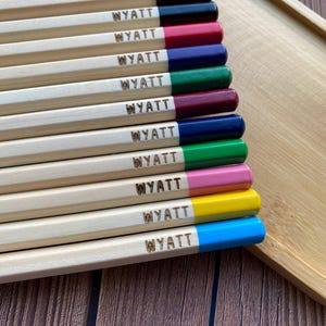 以下が含まれることがあります： 「WYATT」と刻印された木製の鉛筆10本セット。鉛筆はオレンジ、ブラウン、ブラック、レッド、ブルー、グリーン、マルーン、ダークブルー、ピンク、イエロー、ブルーなど、さまざまな色でペイントされています。