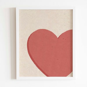 May include: A framed print with a large, red heart shape on a beige background.