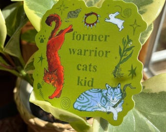 May include: Green sticker with a red cat, a blue cat, and the text "former warrior cats kid". The sticker has a green background with white stars, a white rabbit, and other decorative elements.