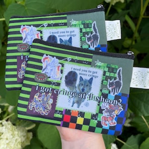 May include: Two small, zippered pouches with a green and black striped pattern. Each pouch features a patchwork design with cartoon images, text that reads "i need you to get more cringe" and "i got cringe at dashcon2".