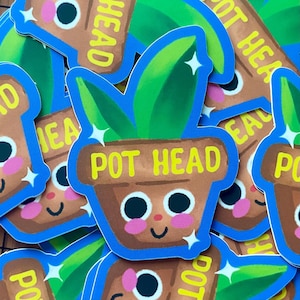 May include: A stack of colorful stickers featuring a cartoon pot with a plant and the text "Pot Head". The pot has a smiling face with big eyes and rosy cheeks. The stickers are perfect for adding a touch of whimsy to your belongings.