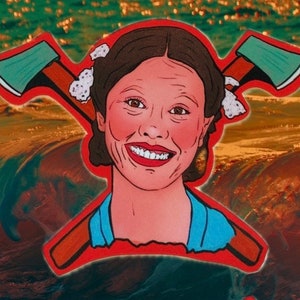 May include: A red, white, and blue sticker with a cartoon image of a woman with a big smile. She has two crossed axes behind her head. The background is a blurry image of water.