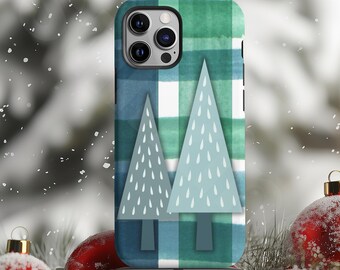 May include: A phone case with a blue and green plaid pattern and two light blue Christmas trees with white accents. The case is surrounded by red ornaments, a wrapped gift, and snowy pine branches.