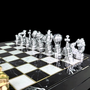 May include: A silver chess set with unique, futuristic-looking pieces on a black and white marble chessboard.