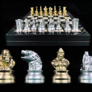 Può includere: Un set di scacchi con pezzi in argento e oro. I pezzi sono scolpiti a immagine di vari mostri, tra cui un gorilla, un dinosauro e una creatura alata. La scacchiera è bianca e nera con una superficie marmorea.