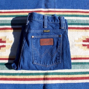 May include: A pair of blue denim jeans with a brown leather patch that says "Wrangler" on the back pocket.