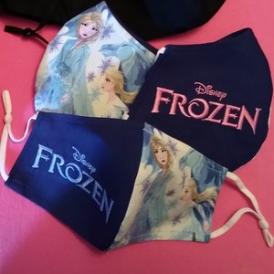 Pu&ograve; includere: Tre maschere in tessuto blu con lacci elastici bianchi per le orecchie. Le maschere hanno uno sfondo bianco con un design Frozen e il testo "Disney Frozen" in ricamo rosa.