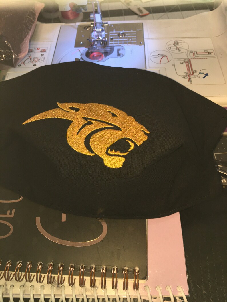 Pu&ograve; includere: Maschera facciale in tessuto nero con un design di testa di pantera ricamata in oro.