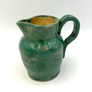 Peut inclure: Pichet en céramique fait à la main avec un glaçage vert. Le pichet a un corps arrondi, un bec verseur et une anse incurvée. L'intérieur est de couleur jaune chaud. Le pichet est adapté pour servir des boissons.