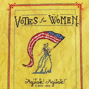 May include: Cross-stitch embroidery of a woman holding an American flag, with the text "Votes for Women" and "Agitate! Agitate! E-Rose-1860" and "nineteenth amendment - august 18, 1920 100 years".