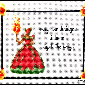 May include: Cross-stitch embroidery of a woman in a red dress holding a torch with the text "may the bridges I burn light the way."