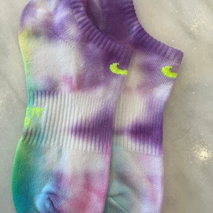 May include: A pair of tie-dye socks in shades of purple, blue, green, and pink. The socks have a white base and are made of a soft, comfortable material.