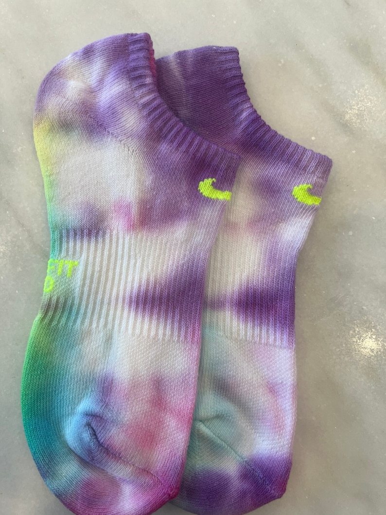 May include: A pair of tie-dye socks in shades of purple, blue, green, and pink. The socks have a white base and are made of a soft, comfortable material.